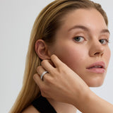 Woman adjusting an earring with a plain background