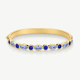 A gold bangle bracelet featuring a row of marquise-cut and round blue gemstones, displayed on a clean white background.