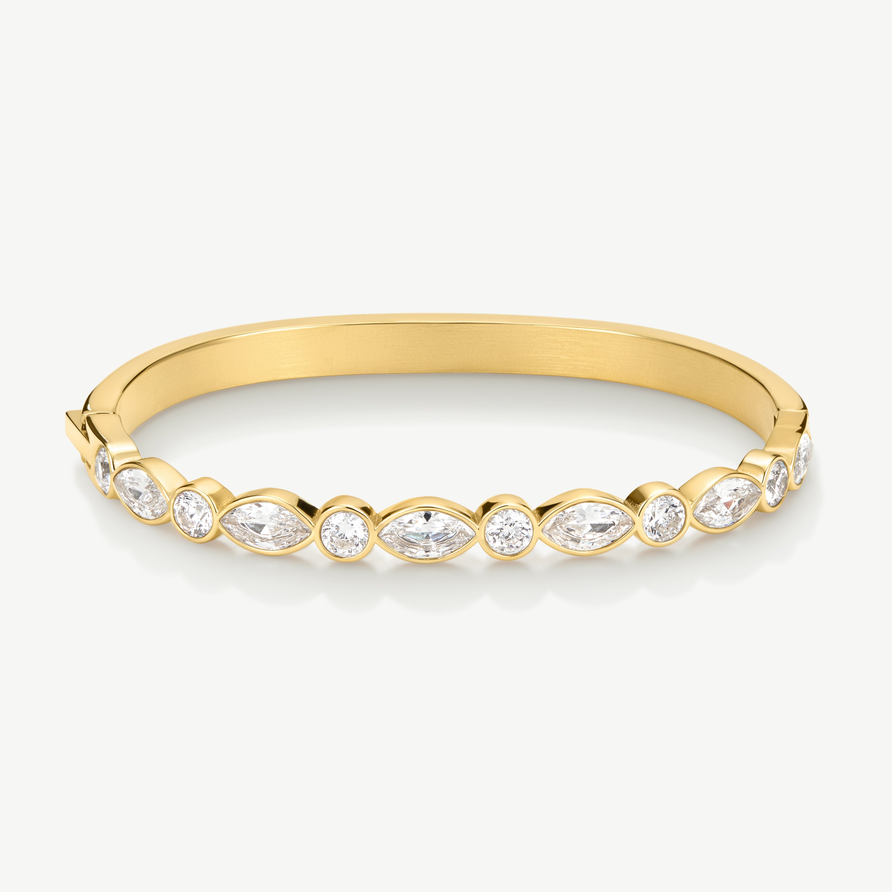 A gold bangle bracelet featuring a row of bezel-set marquise and round clear gemstones, shown on a light gray background.