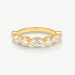 A yellow gold ring featuring a row of clear gemstones in marquise and round cuts, set against a clean off-white background.