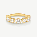 A yellow gold ring featuring a row of clear gemstones in marquise and round cuts, set against a clean off-white background.