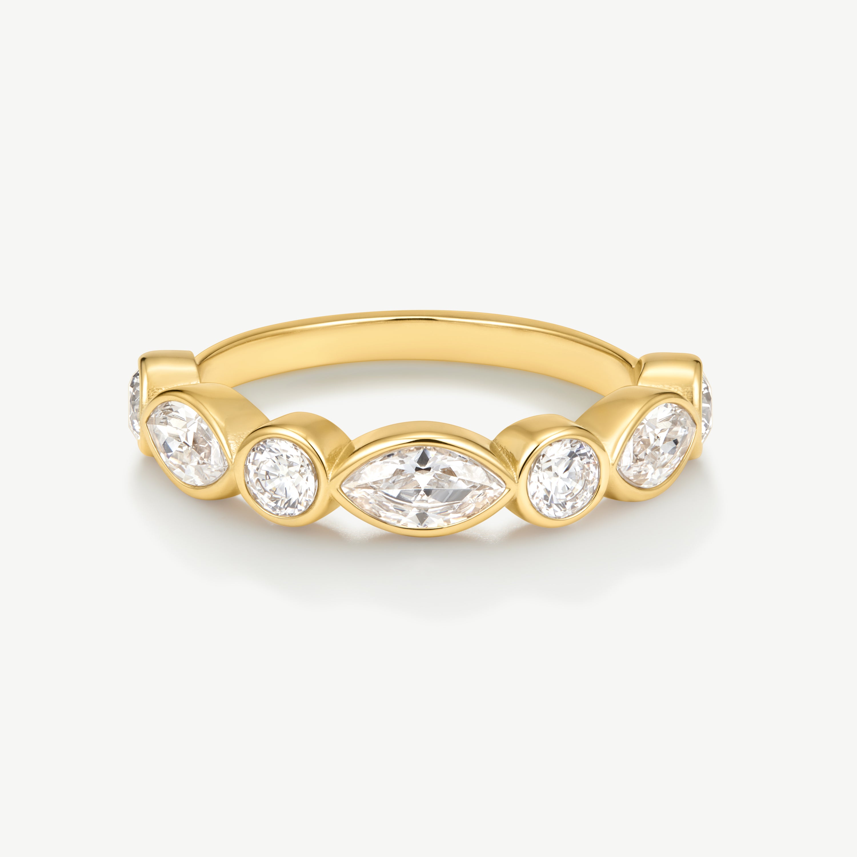 A yellow gold ring featuring a row of clear gemstones in marquise and round cuts, set against a clean off-white background.