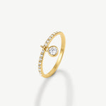 A gold ring featuring a curved band adorned with small clear stones and a round clear center stone, shown on a clean off-white background.