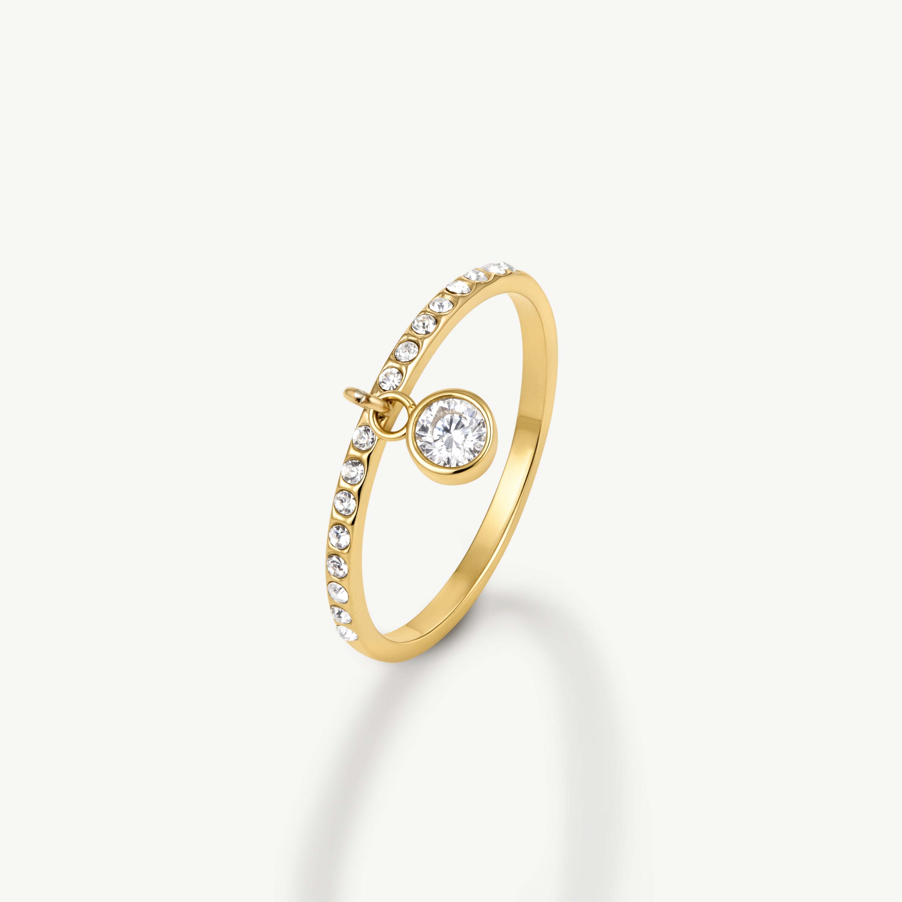 A gold ring featuring a curved band adorned with small clear stones and a round clear center stone, shown on a clean off-white background.