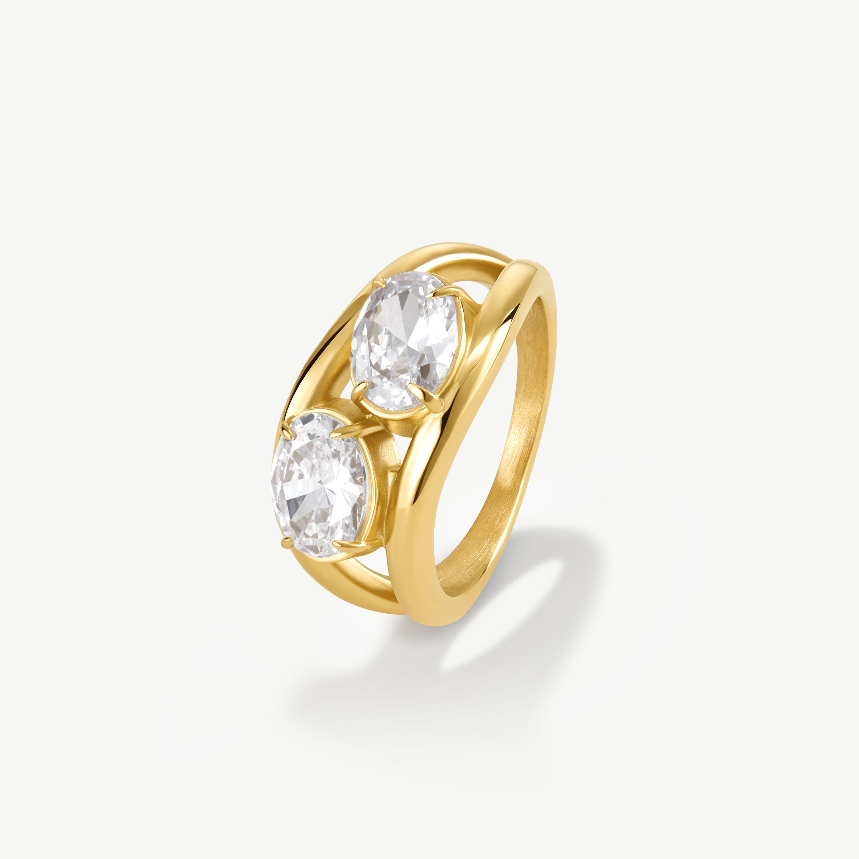 A yellow gold ring featuring three oval-cut clear gemstones in a split, openwork band design, set against a clean off-white background.