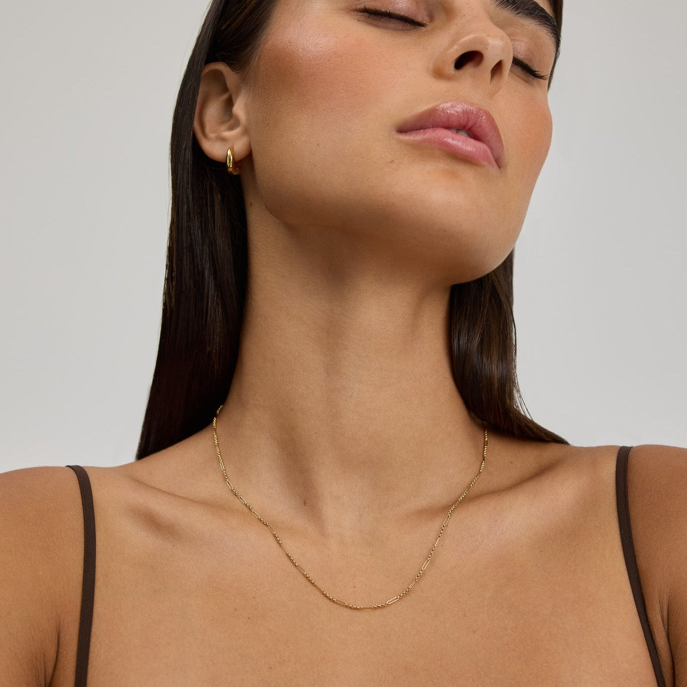 Woman wearing a delicate necklace against a neutral background